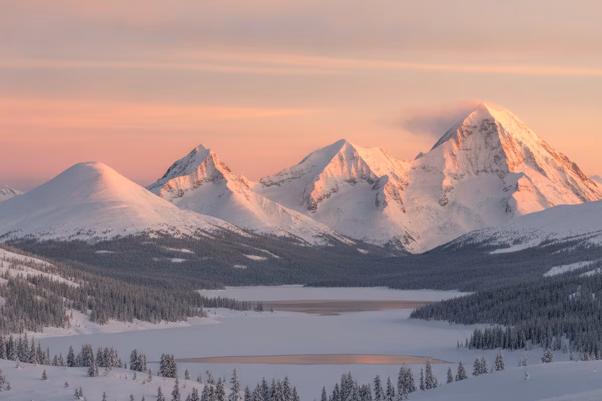 Panorama of four snow-capped peaks rising above an alpine valley